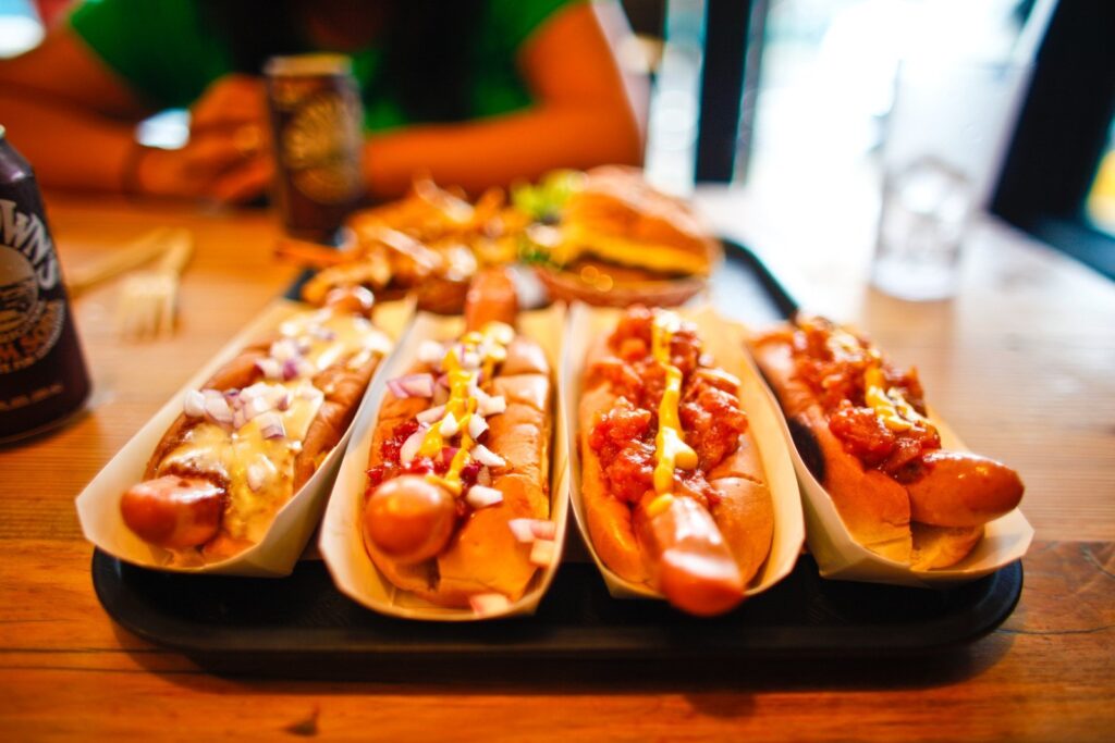Hot dogs com molho de tomate, cebola e mostarda. Os ingredientes variam conforme a receita hot dog