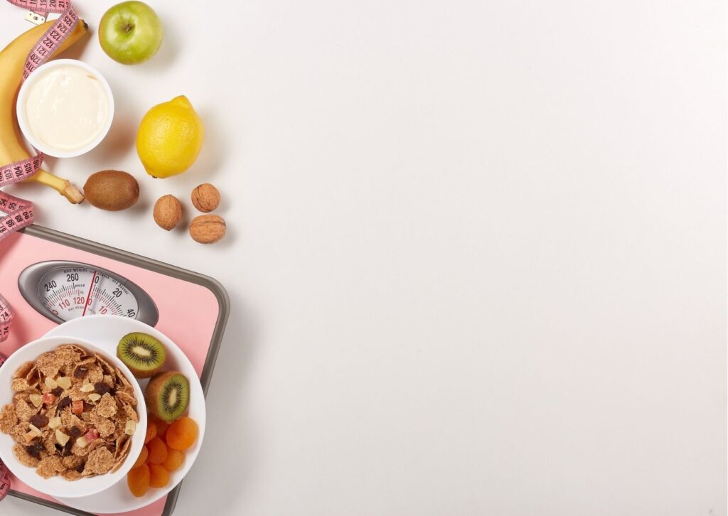 Imagem de fundo claro mostrando uma balança e frutas para ensinar como emagrecer o rosto em 3 dias