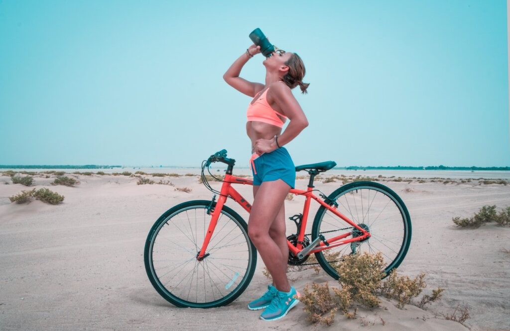 imagem com uma mulher pedalando e bebendo água demonstrando como perder 5 kg em um mês