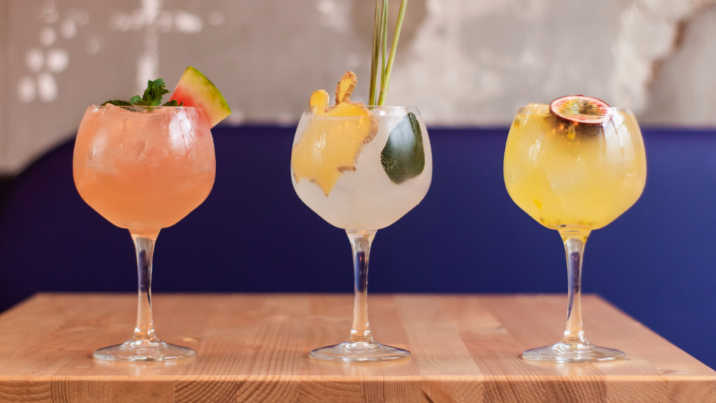 Sobre uma mesa, três taças com diferentes receitas de gin tônica.