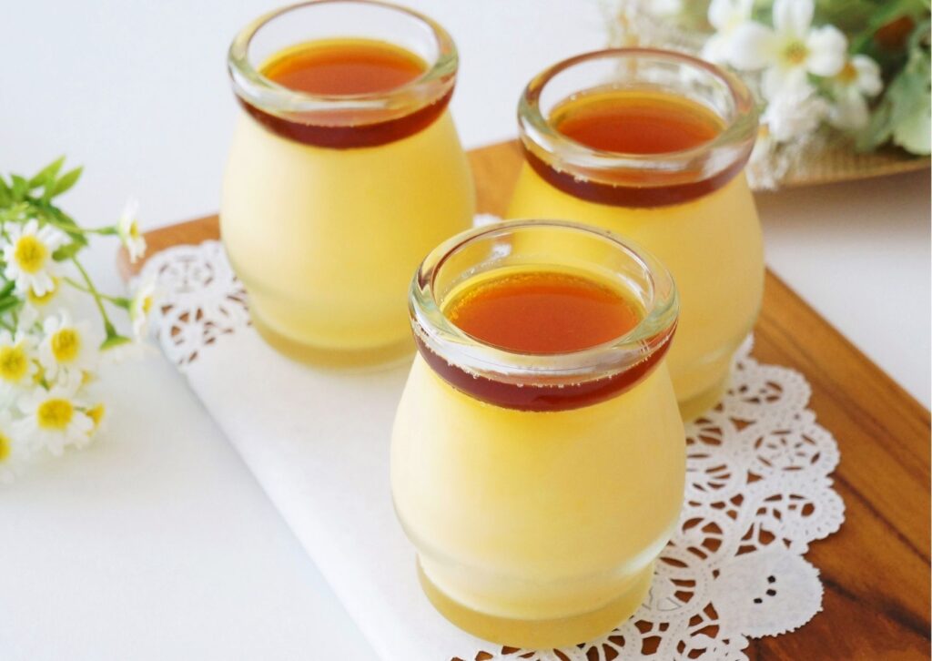 Imagem de mesa posta com pequenos potes de vidros com uma receita de pudim sem leite
