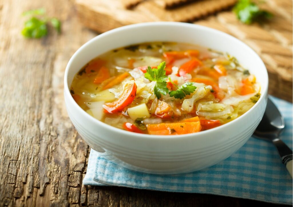 sopa de legumes posta em uma tigela branca, sendo esse um tipo de prato saudável para as refeições