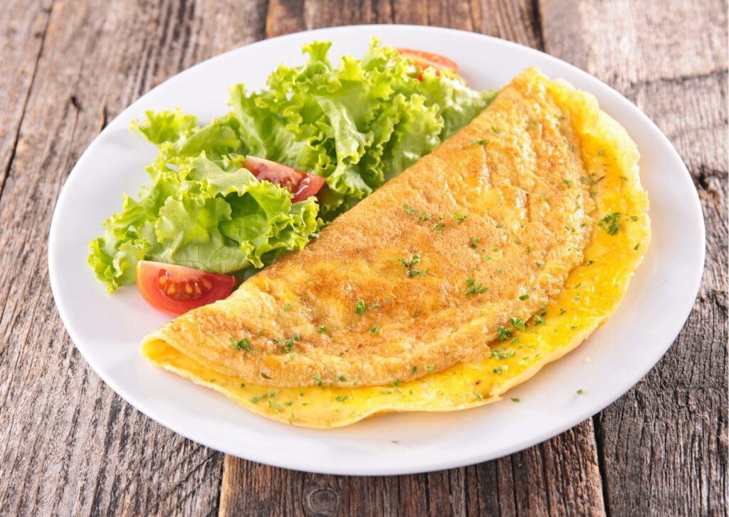 imagem de prato branco com salada e omelete, uma das opções de pratos saudáveis para as refeições