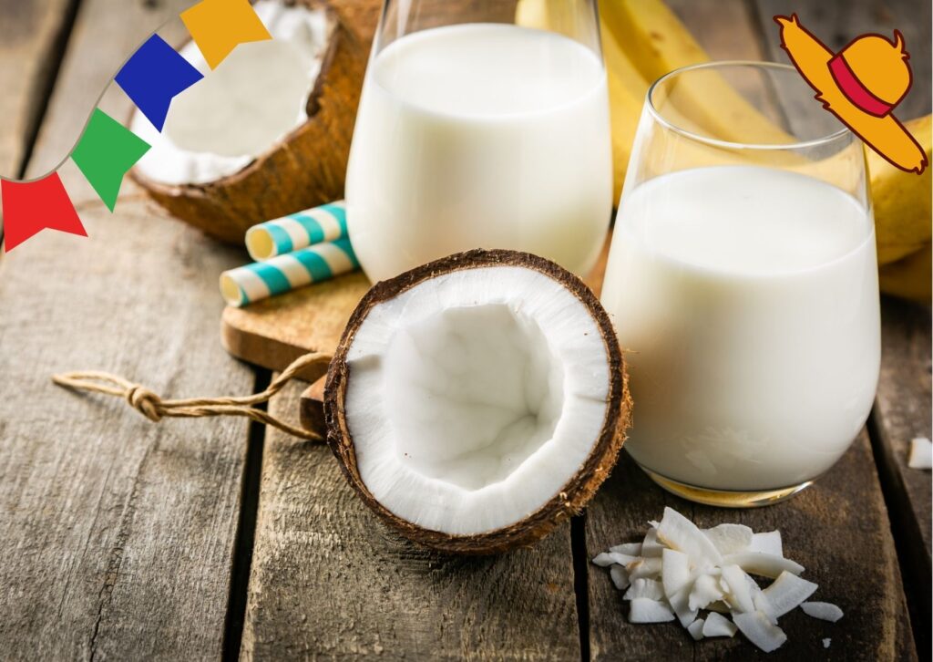 preparo da batida de coco em dois copos transparentes ao fundo; na frente, meio coco seco cortado ao meio