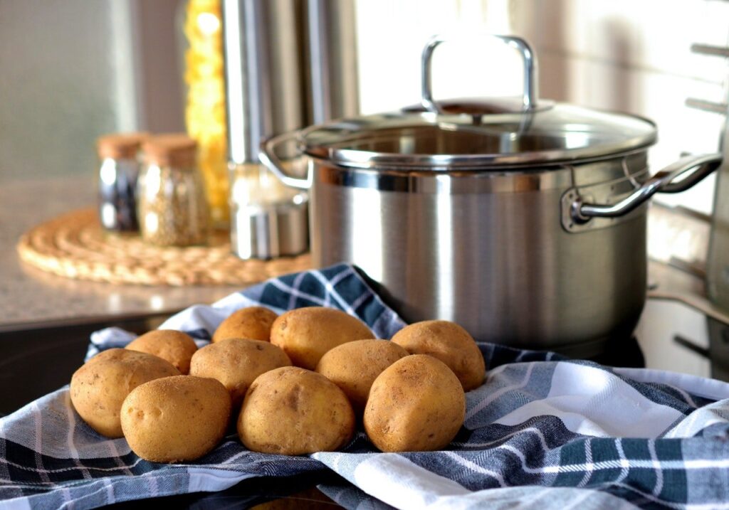 panela de inox ao lado de batatas