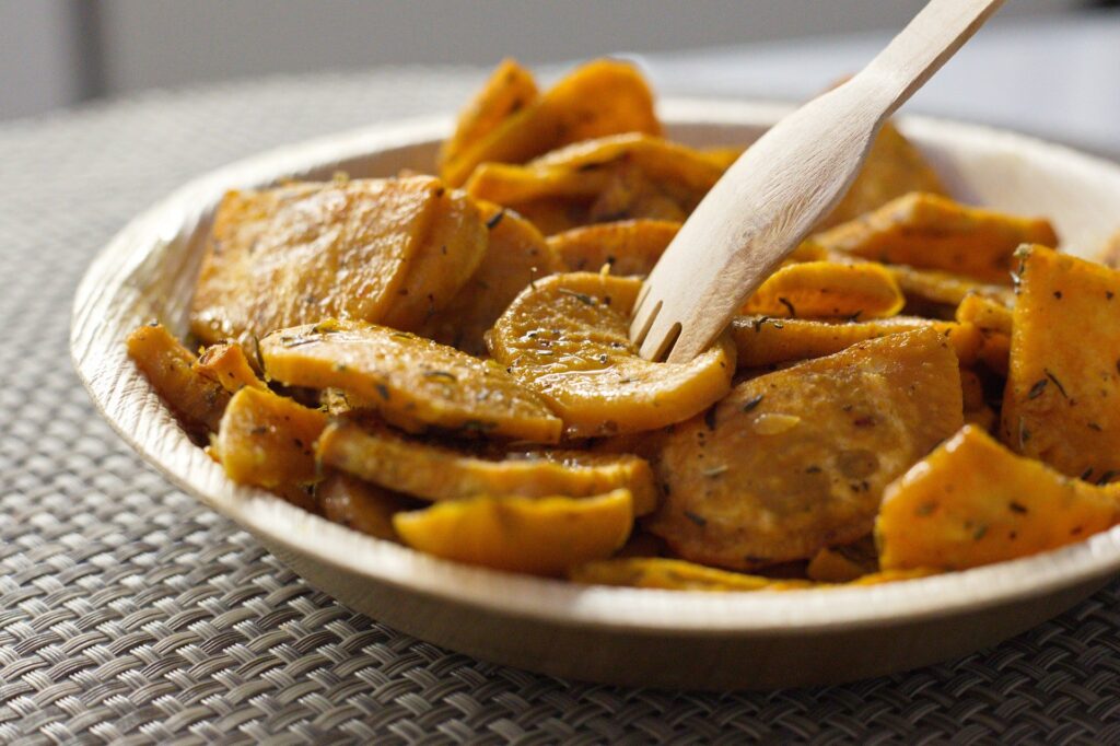 Batata doce cortada e assada em prato, com garfo de madeira. Simbolizando a receita ao forno das receitas com batata doce 