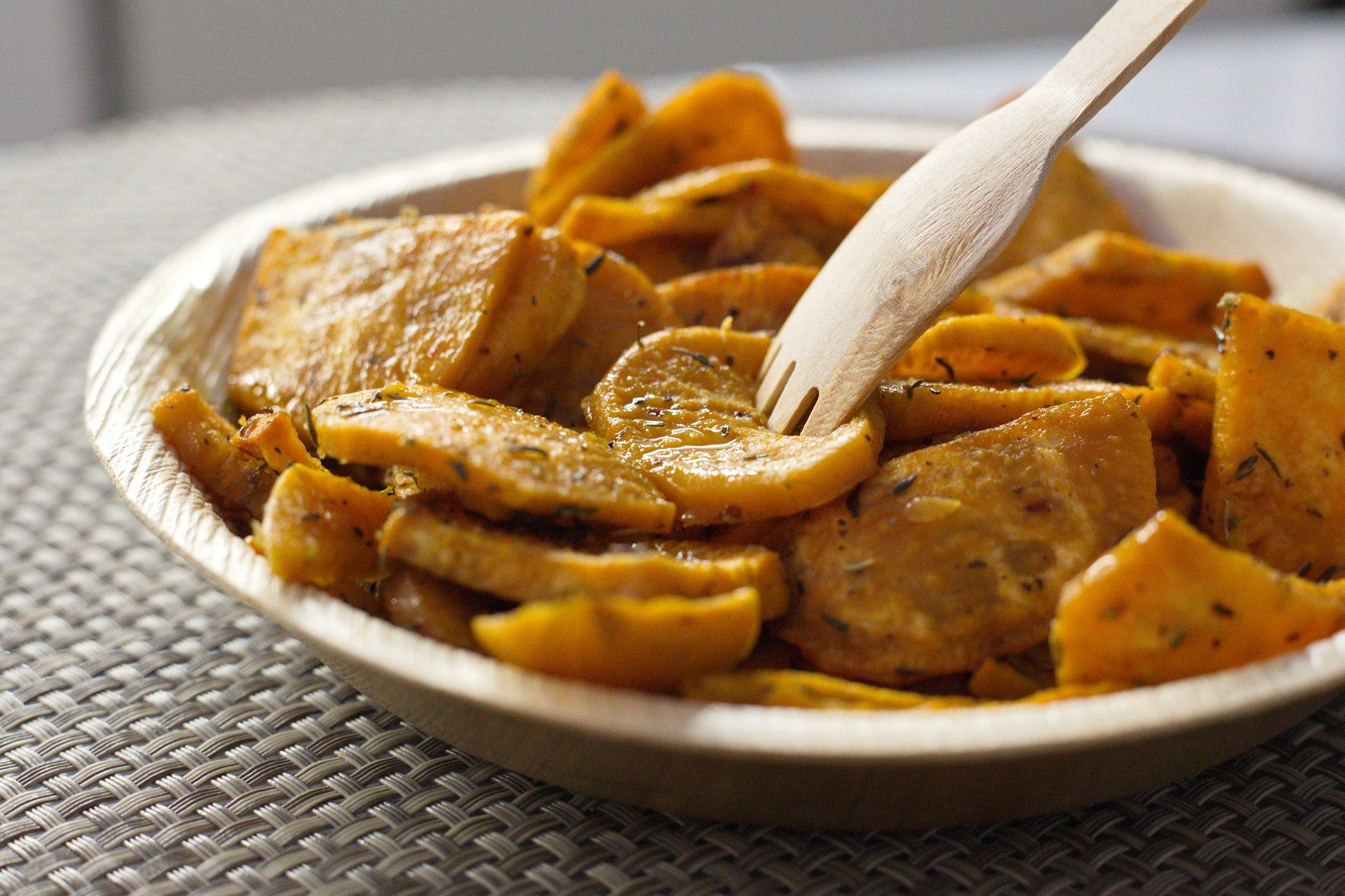 Batata doce cortada e assada em prato, com garfo de madeira. Simbolizando a receita ao forno das receitas com batata doce