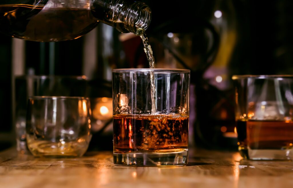 Bartender serve whisky em mesa de madeira