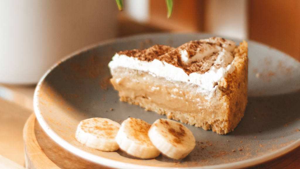Fatia de banoffe simples com três pequenas fatias de banana ao lado, também dentro do prato