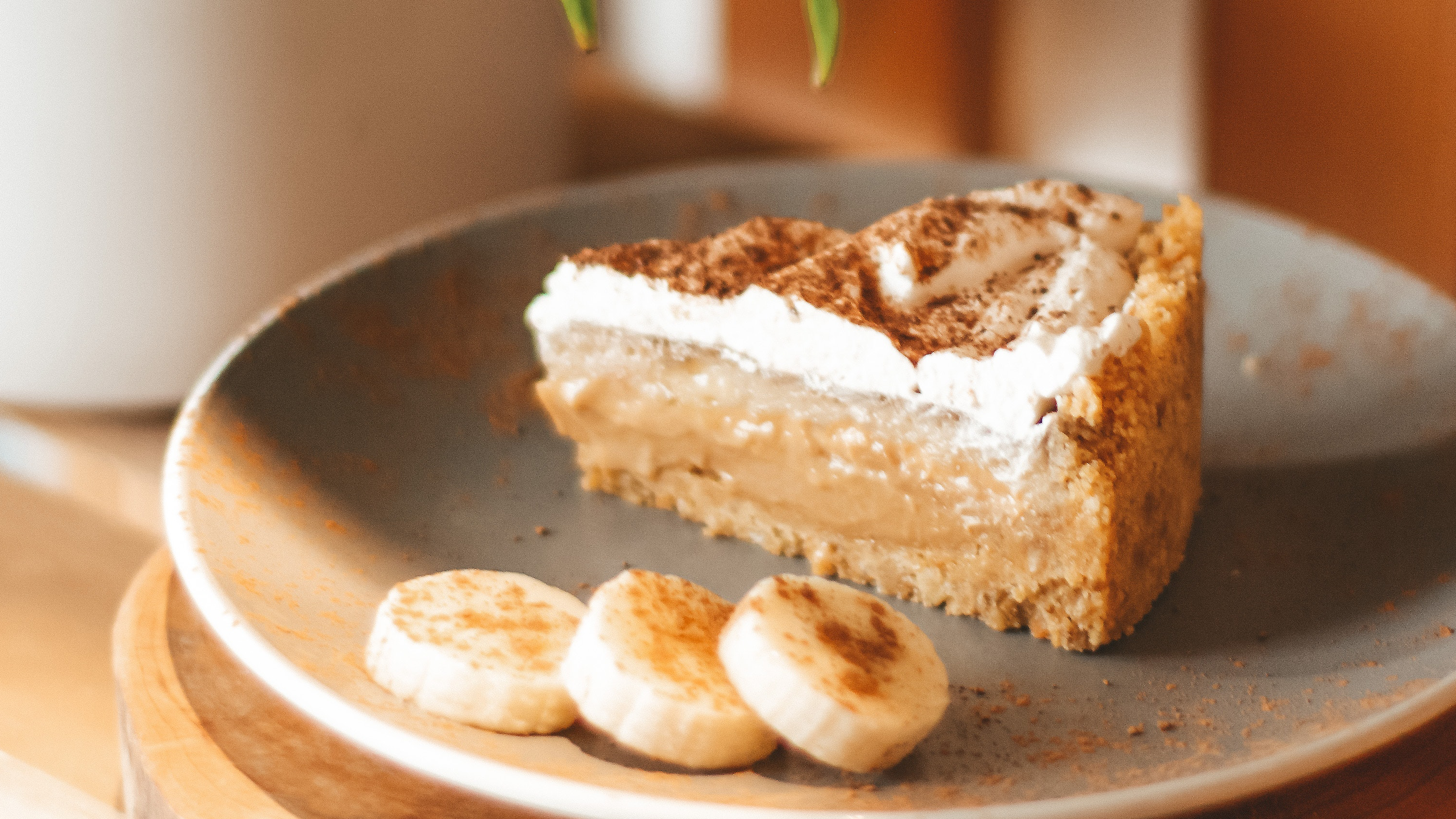 Fatia de banoffe simples com três pequenas fatias de banana ao lado, também dentro do prato