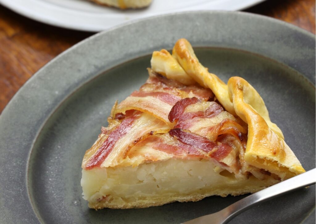 Imagem com um bolo salgado de palmito e bacon no prato cinza