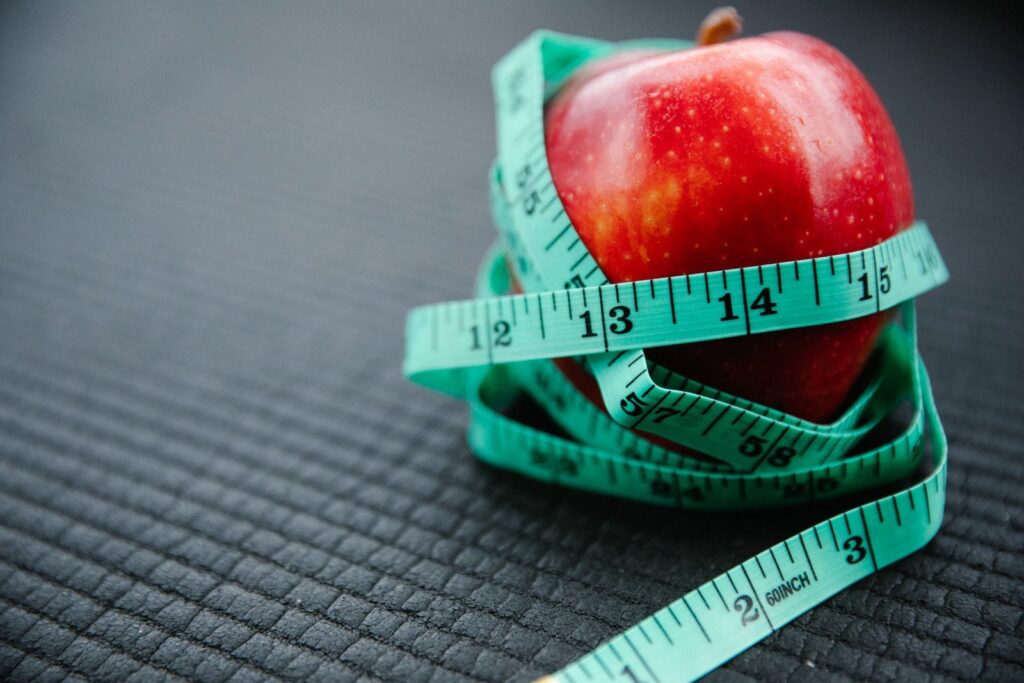 Maçã envolta em fita métrica, simbolizando fruta para emagrecer