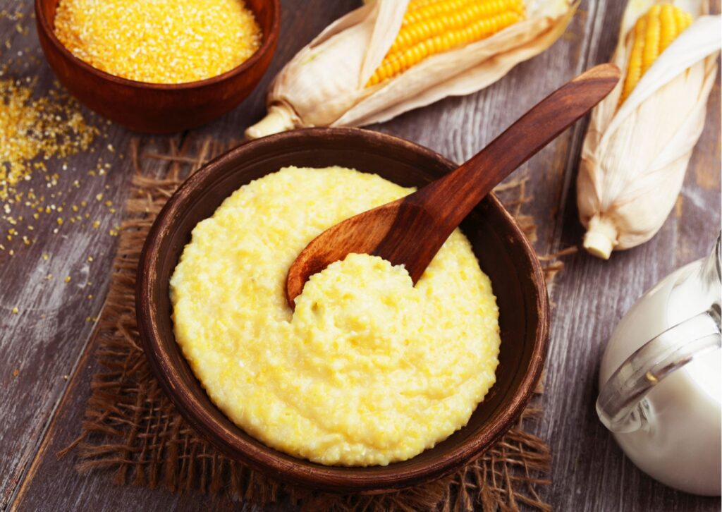 Imagem com um milho ao fundo mostrando um prato de polenta super cremosa