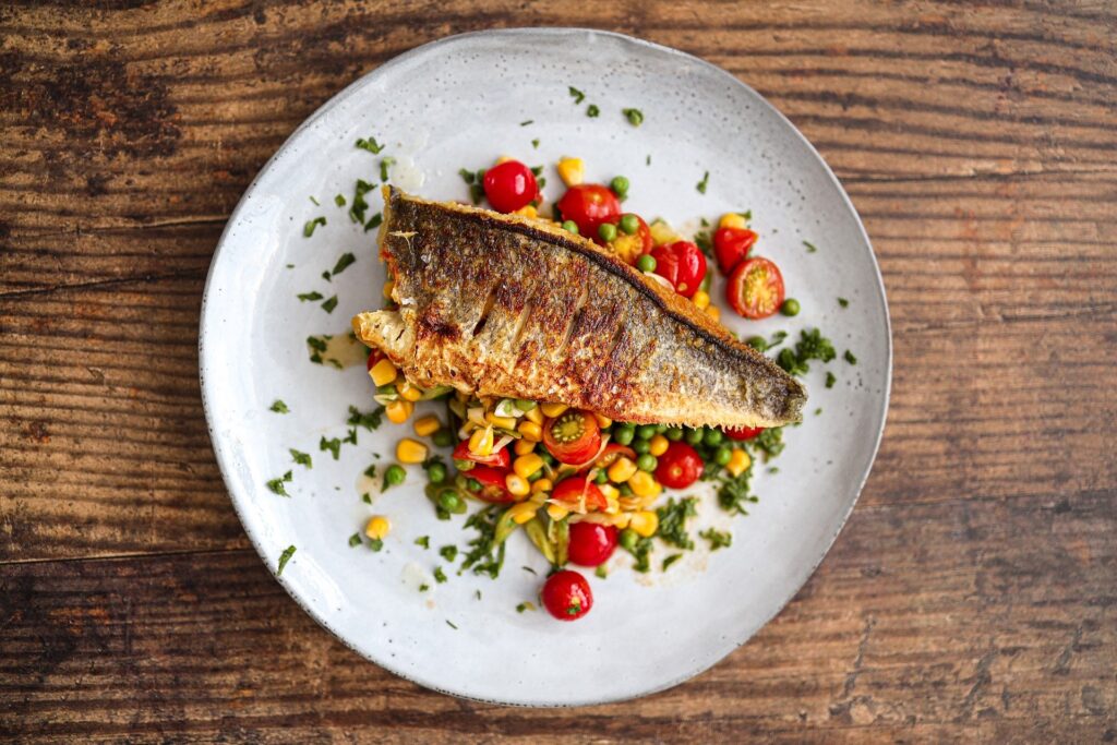 Receita com peixe chinês com mini tomates, milho e ervilha simbolizando iguarias orientais