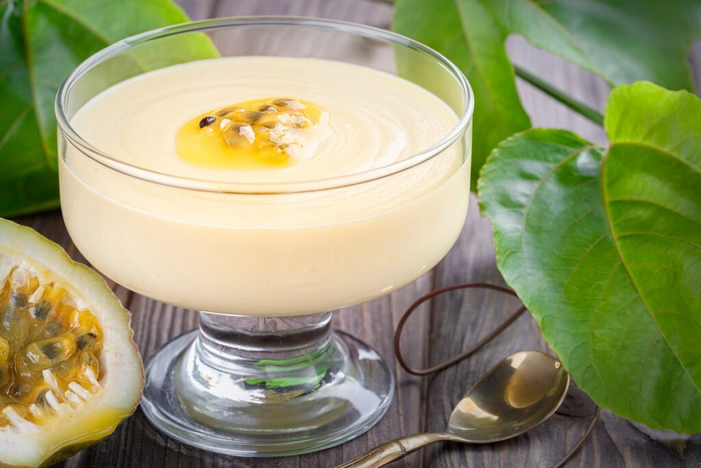 mousse de maracujá com gelatina em taça de vidro ao lado de uma colher