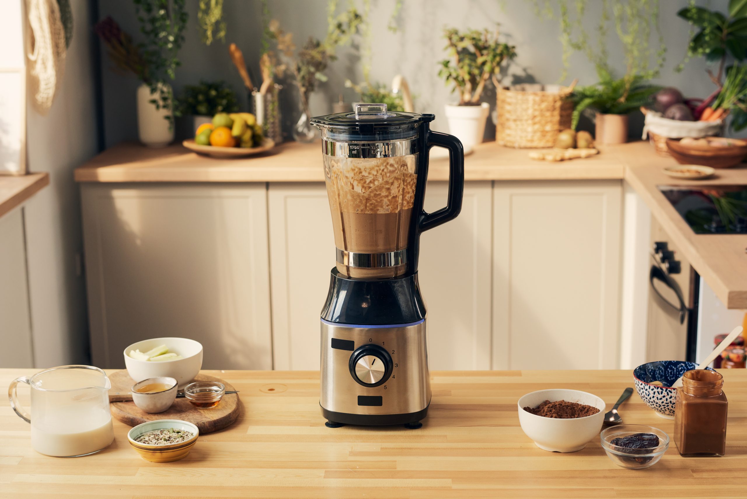 Liquidificador elétrico com vitamina de chocolate e tigelas com ingredientes