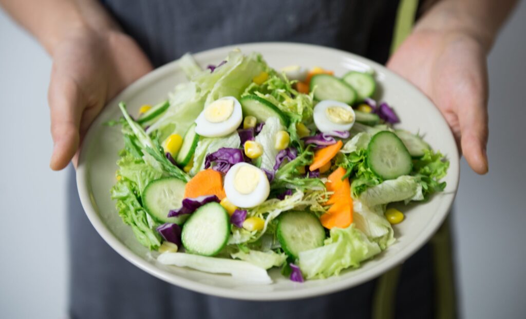 salada com ovos, legumes e verduras variadas em prato branco.