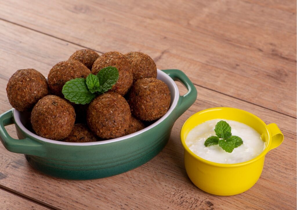 imagem com o quibe vegano de forno servido em uma travessa com um delicioso molho com hortelã