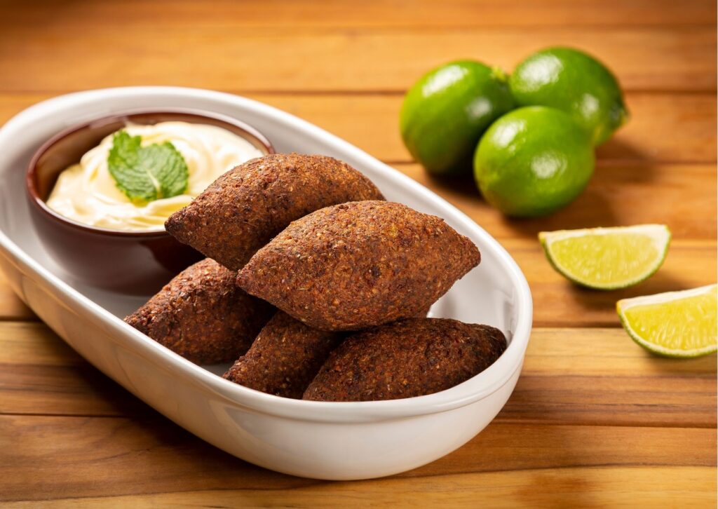 imagem com o quibe vegano de forno servido em uma travessa com um delicioso molho com hortelã