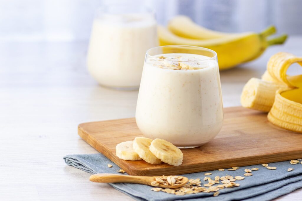 Iogurte natural caseiro de banana em frasco de vidro sobre o fundo claro.