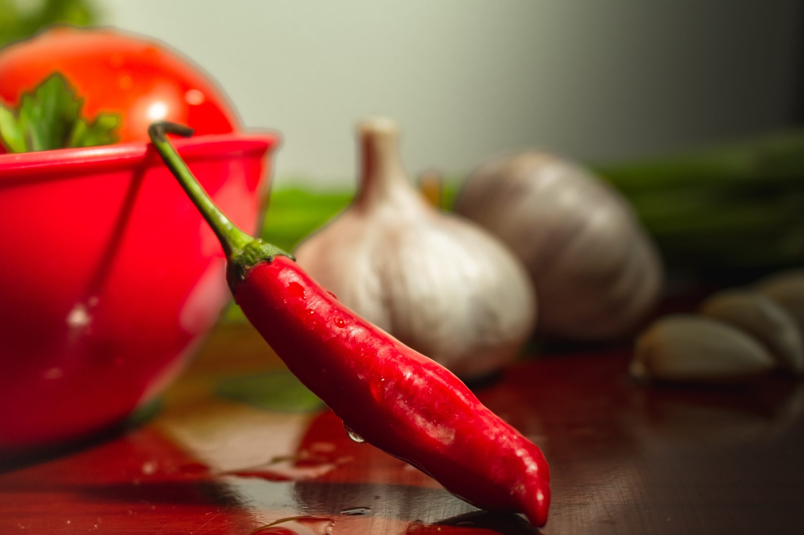 Pimenta dedo-de-moça e alho desfocado ao fundo.