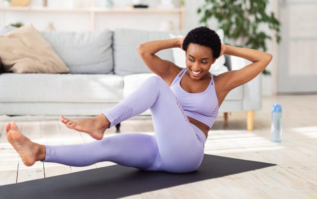 Mulher negra tendo treinamento doméstico, exercitando-se na sala de estar