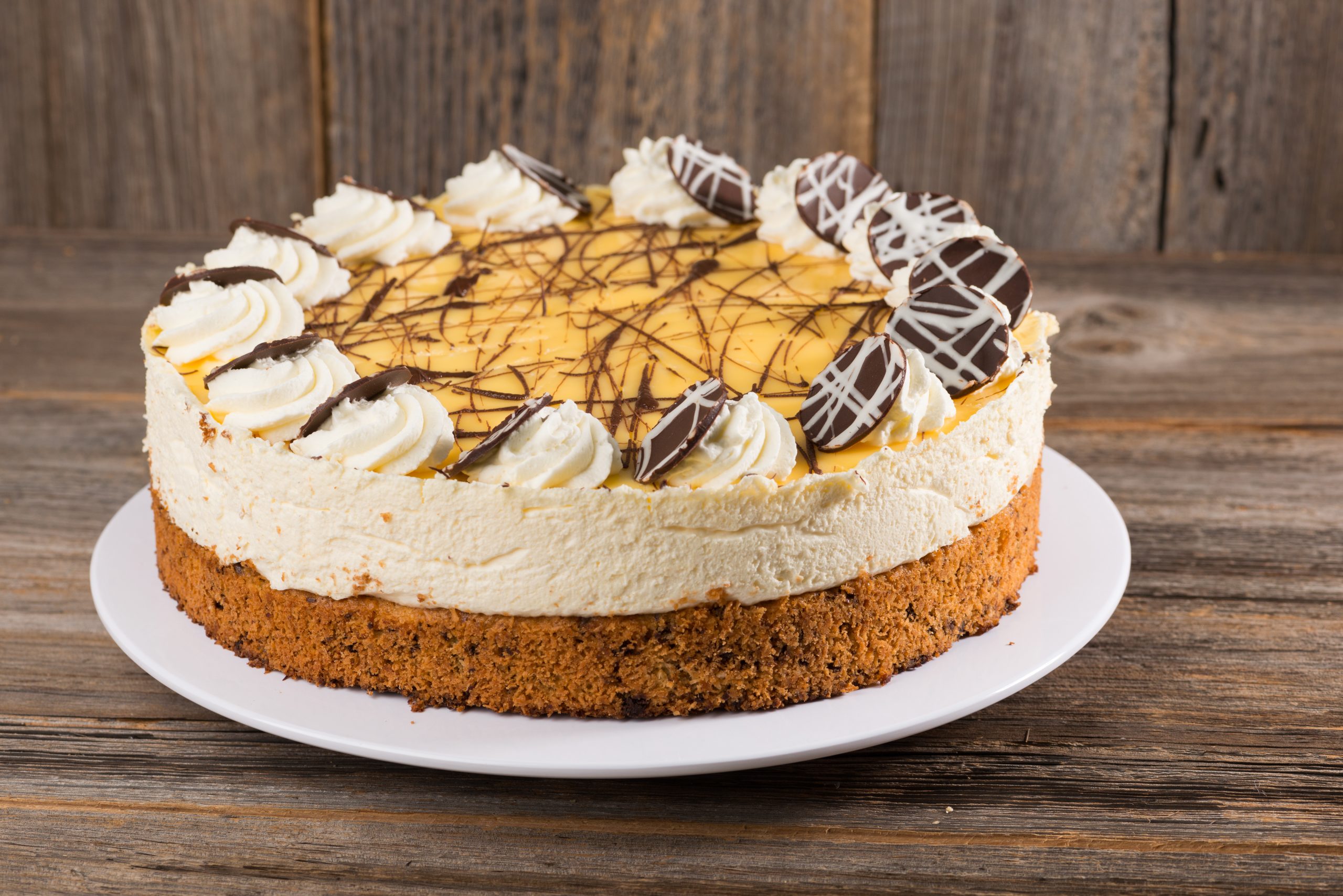 Torta decorada em prato branco em cima de mesa de madeira.