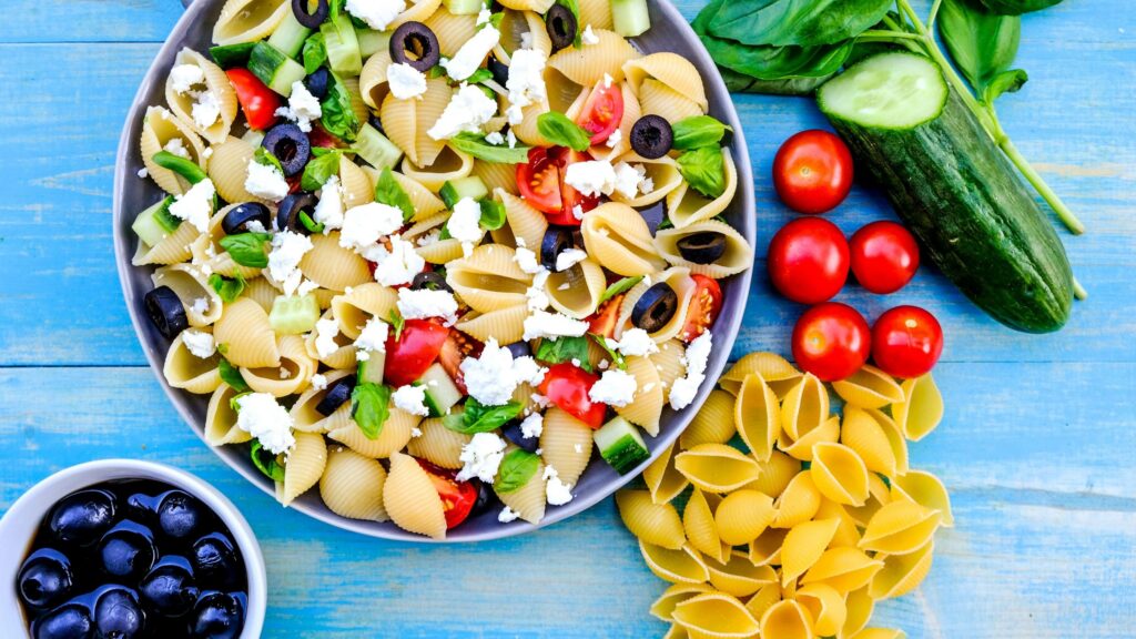 salada de macarrão em pote ao lado de ingredientes frescos
