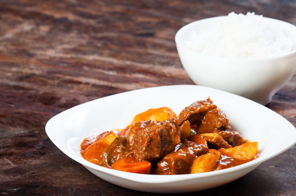 Carne ensopada com batatas em prato branco.