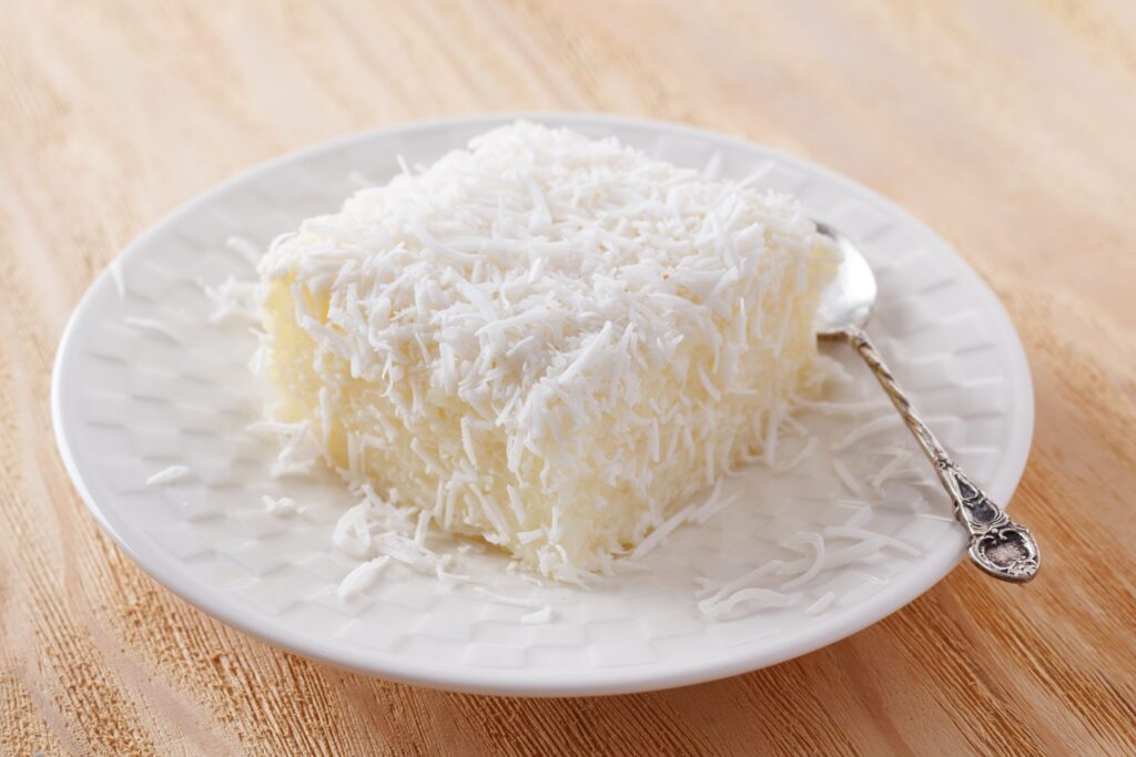 bolo de tapioca com coco em prato branco.