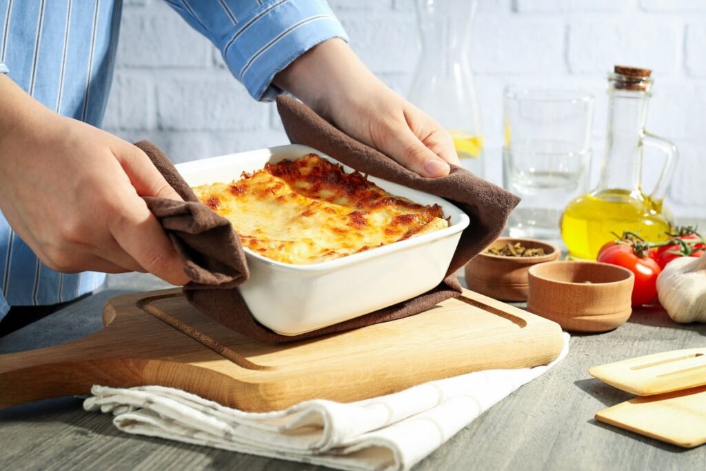 Pessoa colocando travessa com escondidinho na mesa