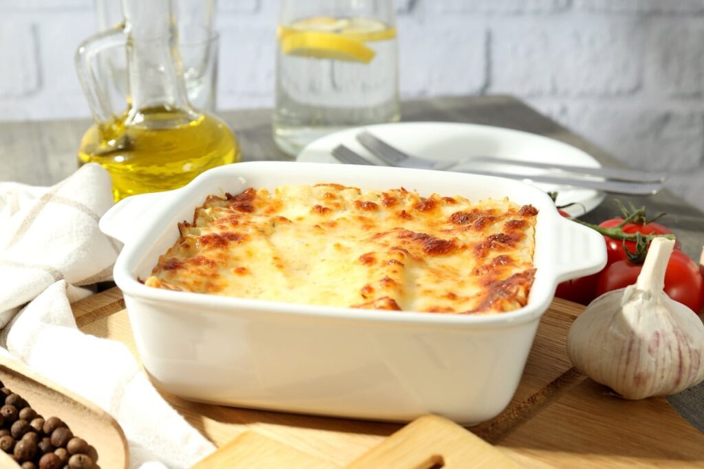Escondidinho de carne moída em cima de mesa, pratos, talheres, azeite