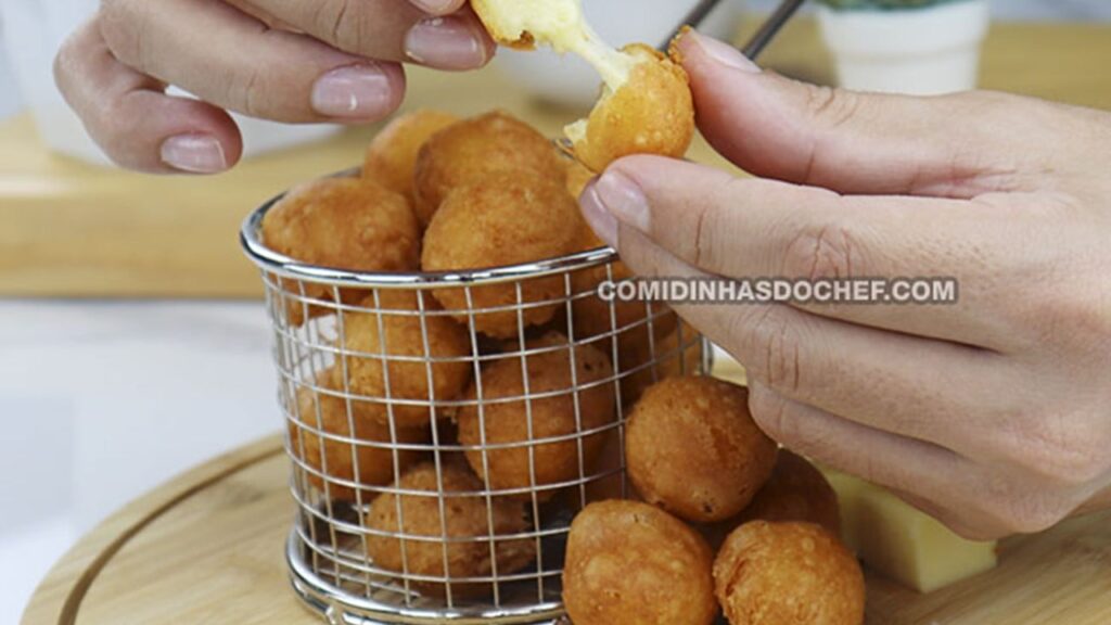 Mão partindo bolinhas de queijo